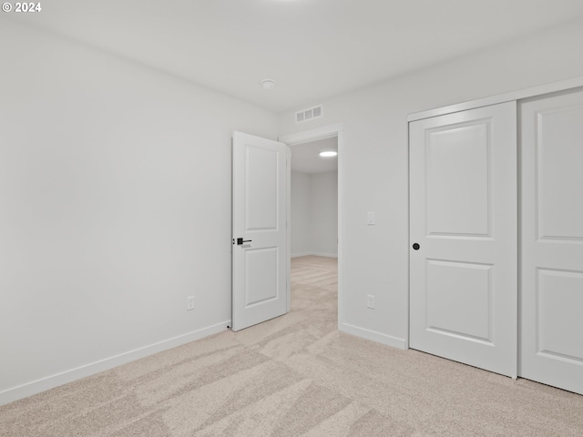 unfurnished bedroom featuring light carpet and a closet