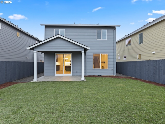 rear view of house with a patio and a lawn