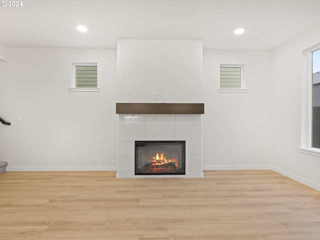 unfurnished living room featuring a tile fireplace and light wood-type flooring