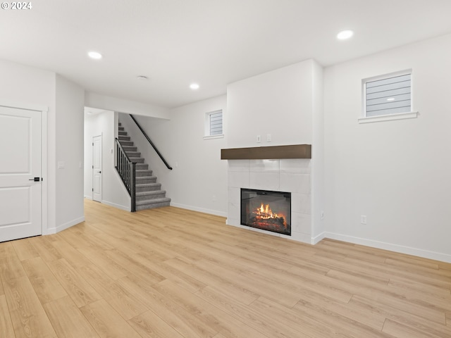 unfurnished living room with a tile fireplace and light hardwood / wood-style flooring