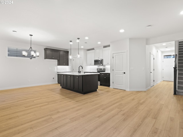 kitchen with a center island with sink, light hardwood / wood-style floors, white cabinetry, and stainless steel appliances