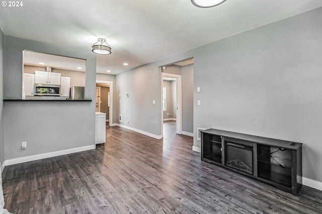 unfurnished living room with dark wood-type flooring, recessed lighting, and baseboards