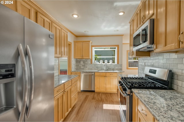 kitchen featuring sink, tasteful backsplash, light hardwood / wood-style flooring, appliances with stainless steel finishes, and light stone countertops