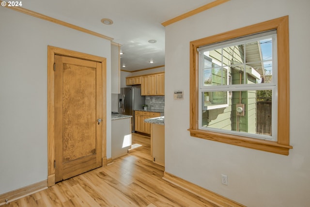 kitchen featuring light brown cabinetry, crown molding, light hardwood / wood-style floors, and decorative backsplash