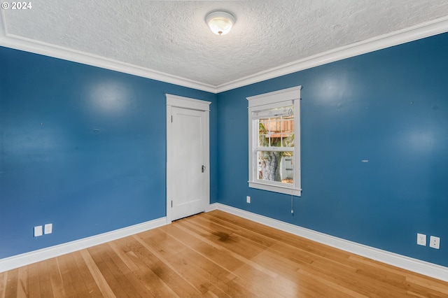 spare room featuring a textured ceiling, wood-type flooring, and crown molding