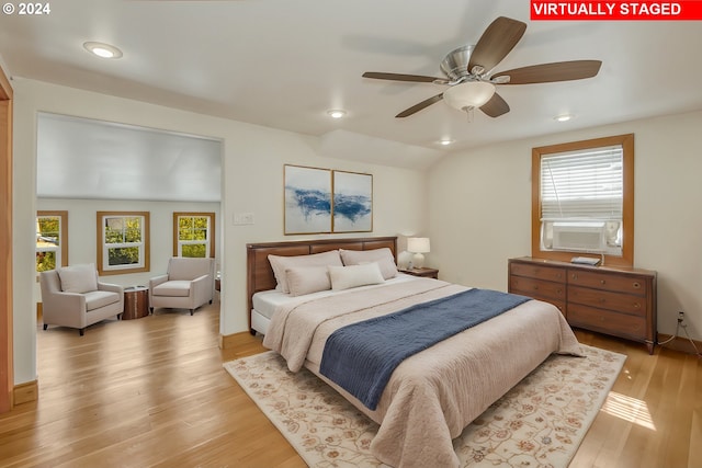 bedroom featuring light wood-type flooring, cooling unit, vaulted ceiling, and ceiling fan