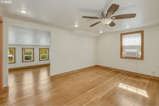 spare room with light hardwood / wood-style flooring, cooling unit, lofted ceiling, and ceiling fan