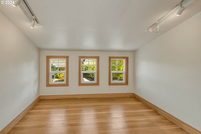 unfurnished room featuring light hardwood / wood-style flooring, plenty of natural light, and rail lighting