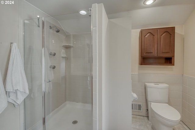 bathroom with tile walls, a shower with shower door, and toilet