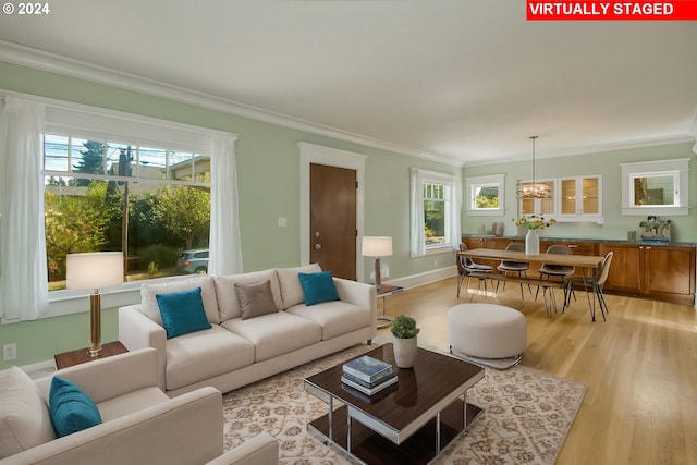 living room featuring light hardwood / wood-style floors, ornamental molding, and a chandelier