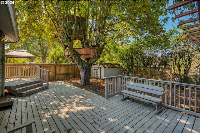 wooden terrace featuring a storage unit and a gazebo