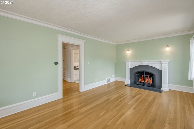 unfurnished living room with a textured ceiling, light hardwood / wood-style floors, and crown molding