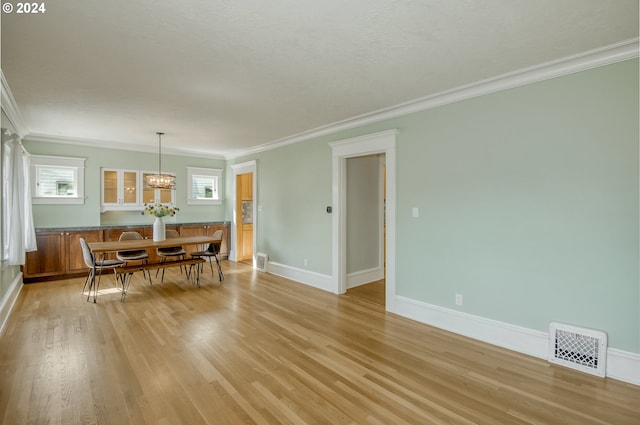 dining area featuring a notable chandelier, light wood-type flooring, and ornamental molding