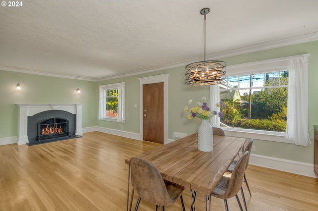 dining area with light wood-type flooring, ornamental molding, and a notable chandelier