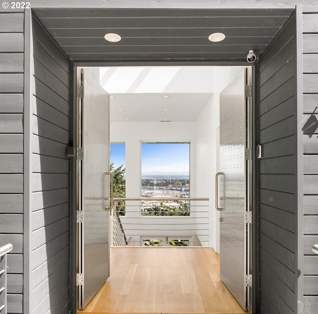 corridor with wood walls and light hardwood / wood-style flooring