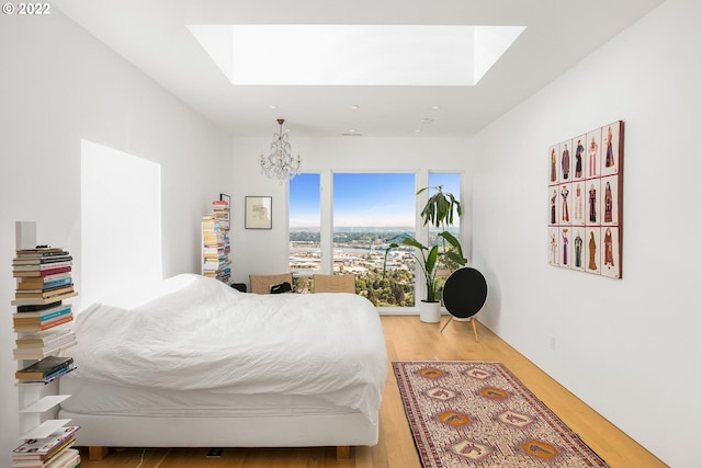 bedroom featuring a notable chandelier, wood-type flooring, and a skylight