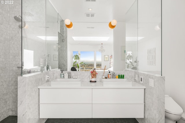 bathroom featuring vanity, toilet, tile walls, and tiled shower