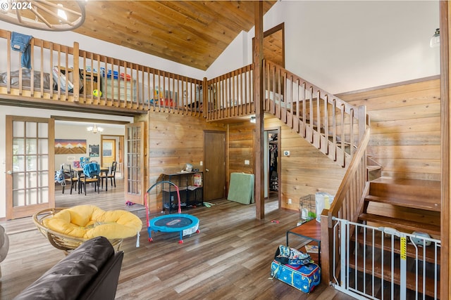 living room with hardwood / wood-style flooring, high vaulted ceiling, a chandelier, and wooden walls