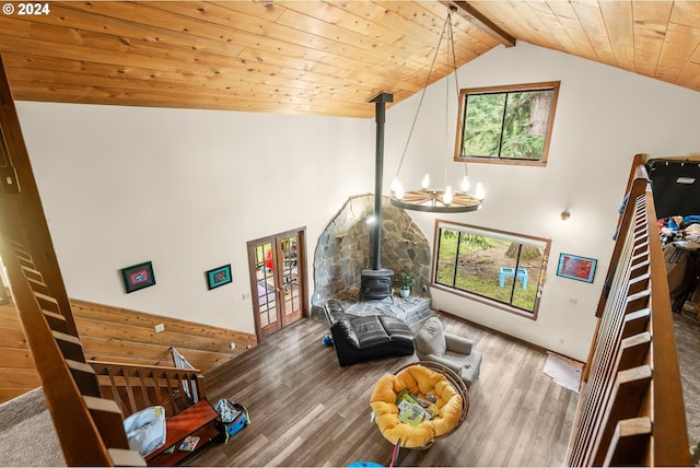 living room with hardwood / wood-style flooring, beamed ceiling, a wood stove, wooden ceiling, and an inviting chandelier