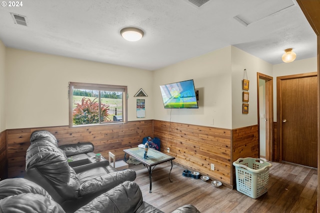 living room with wood walls, hardwood / wood-style floors, and a textured ceiling