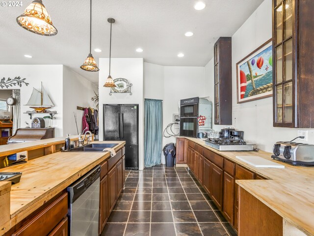 kitchen featuring sink, dishwasher, dark tile patterned flooring, and wood counters