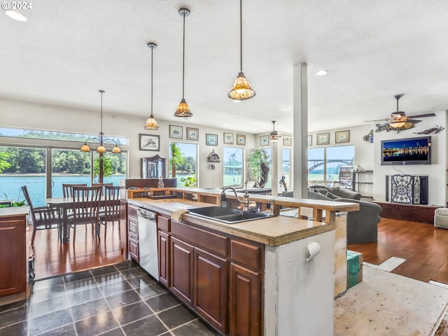 kitchen featuring white dishwasher, ceiling fan, dark tile patterned flooring, pendant lighting, and sink