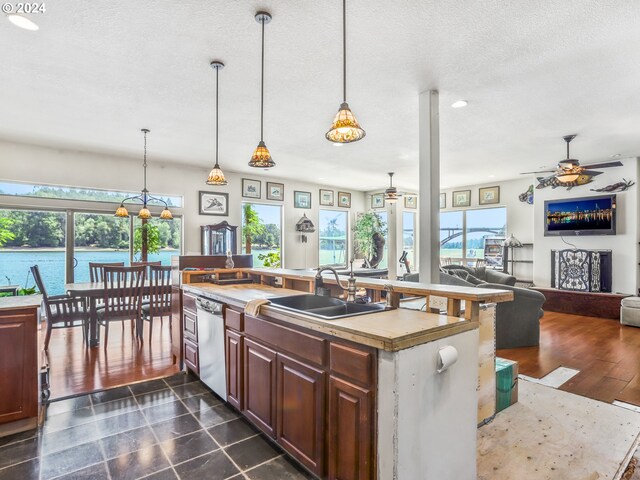 kitchen with pendant lighting, sink, dishwasher, a water view, and a center island with sink