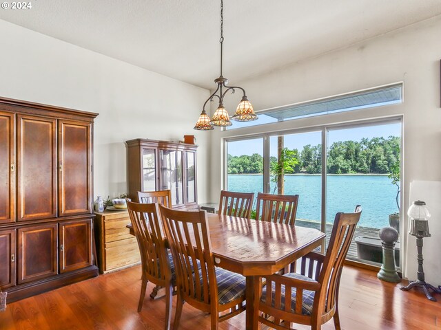 dining room with wood-type flooring, a notable chandelier, and a water view