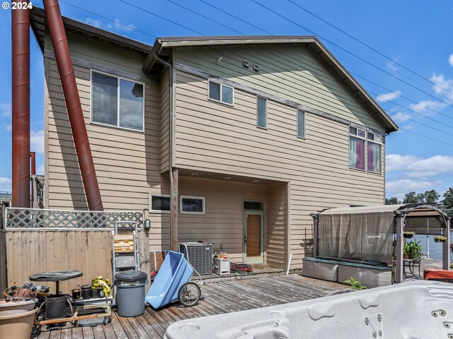 back of property featuring a hot tub, a gazebo, cooling unit, and a deck