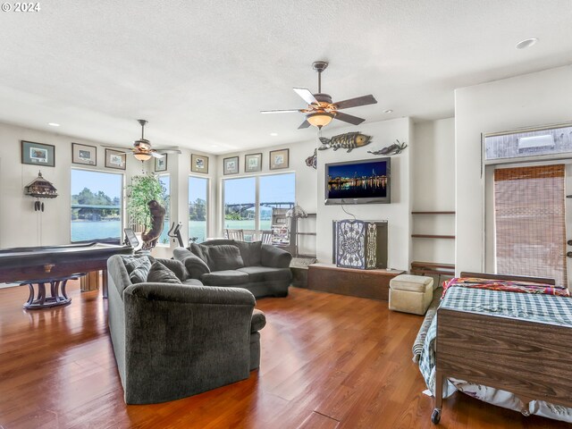 living room featuring ceiling fan, a textured ceiling, hardwood / wood-style flooring, and pool table