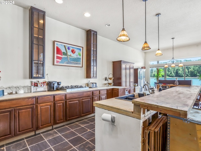 kitchen featuring dark tile patterned floors, decorative light fixtures, sink, and a textured ceiling