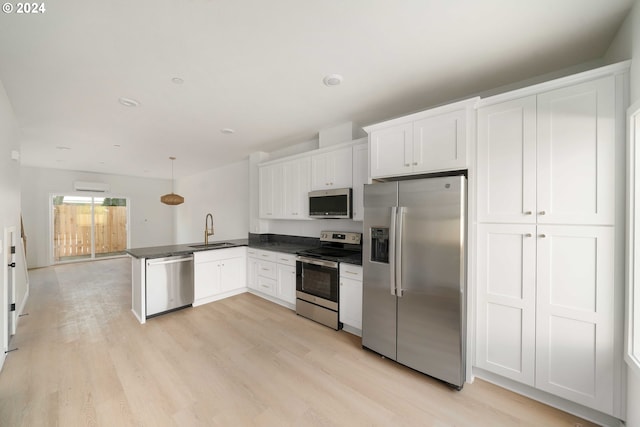 6061 NE Simpson St, Portland, OR 97218 - kitchen featuring appliances with stainless steel finishes, a peninsula, dark countertops, and light wood finished floors