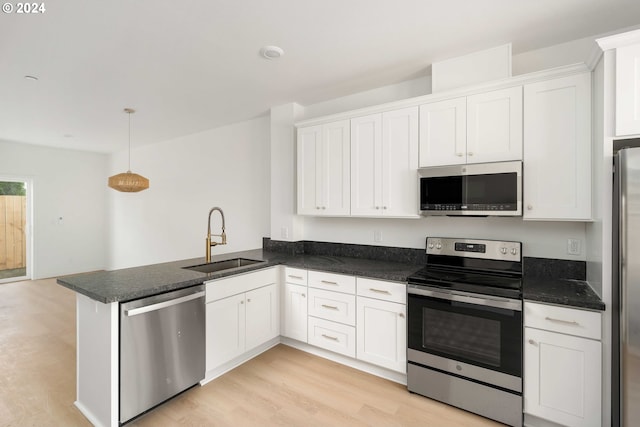 6061 NE Simpson St, Portland, OR 97218 - kitchen with appliances with stainless steel finishes, a peninsula, white cabinets, and light wood finished floors