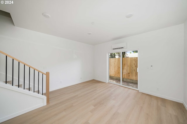 empty room with light hardwood / wood-style floors and an AC wall unit