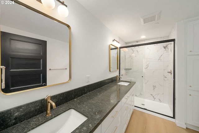 6061 NE Simpson St, Portland, OR 97218 - bathroom featuring a marble finish shower, double vanity, wood finished floors, and recessed lighting