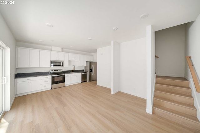 6061 NE Simpson St, Portland, OR 97218 - kitchen featuring stainless steel appliances, dark countertops, light wood-style floors, and white cabinets
