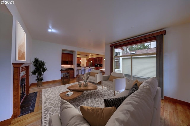 living room with light wood-type flooring and a tiled fireplace