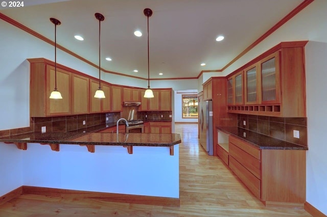 kitchen with kitchen peninsula, a kitchen breakfast bar, stainless steel appliances, pendant lighting, and light hardwood / wood-style floors