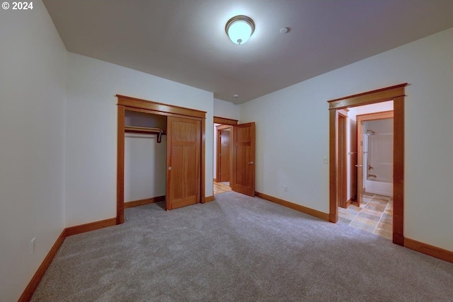 unfurnished bedroom with light colored carpet and a closet