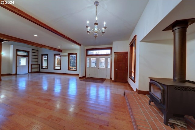 foyer entrance with beamed ceiling, light hardwood / wood-style floors, an inviting chandelier, and plenty of natural light