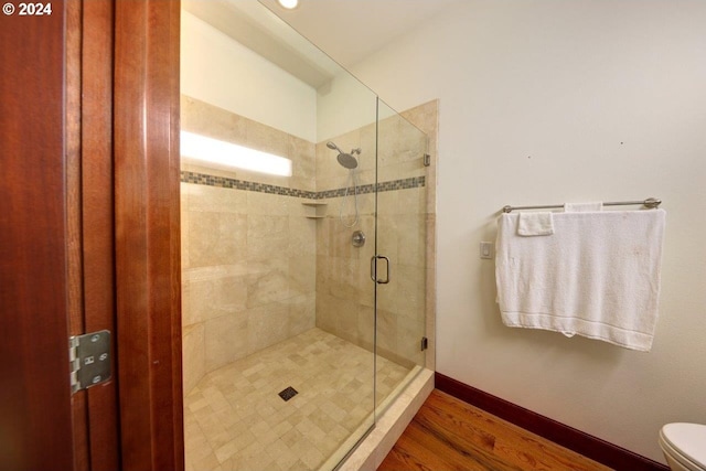 bathroom with hardwood / wood-style flooring, toilet, and an enclosed shower