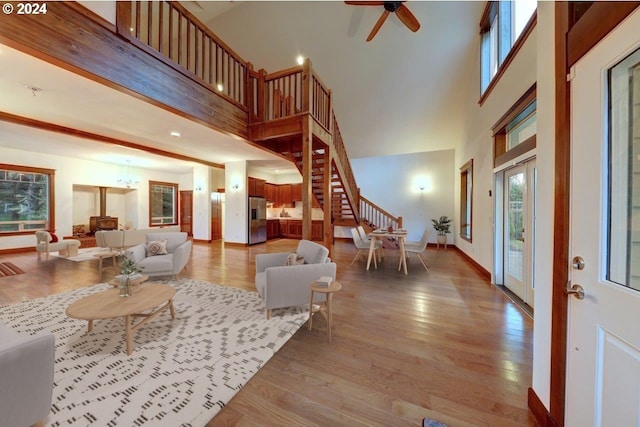 living room with ceiling fan, a towering ceiling, and hardwood / wood-style flooring