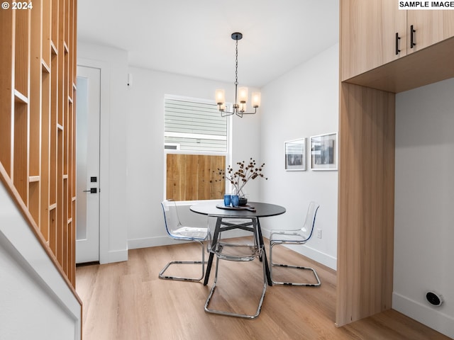 dining area with light hardwood / wood-style flooring and a notable chandelier