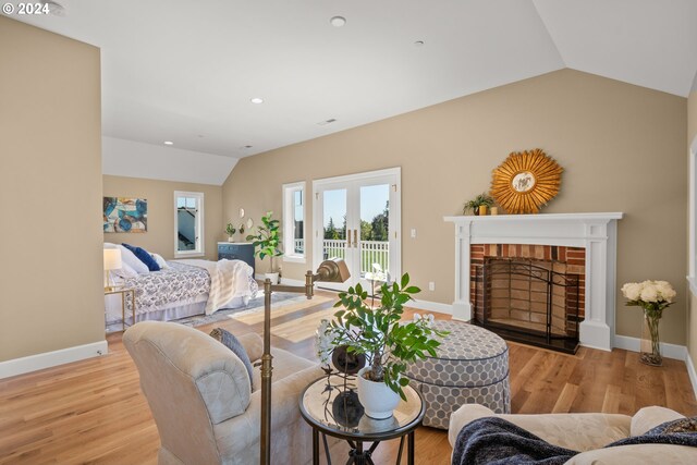 sitting room featuring a brick fireplace, light hardwood / wood-style floors, and lofted ceiling