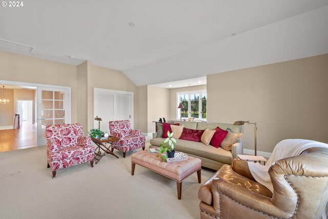 carpeted living room featuring lofted ceiling and a chandelier