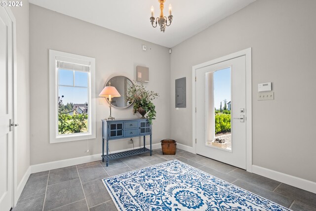 tiled entryway with electric panel and a notable chandelier