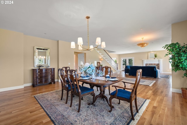 35222 NE 92nd Ct, La Center, WA 98629 - dining area featuring stairway, light wood finished floors, a brick fireplace, baseboards, and an inviting chandelier