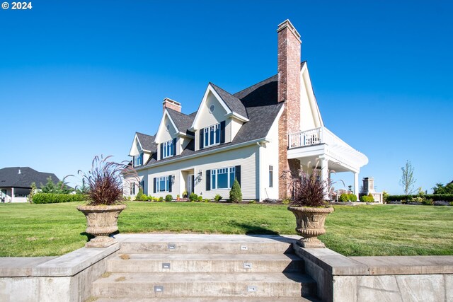 view of front of property featuring a balcony and a front lawn