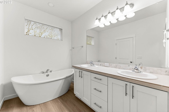 bathroom featuring wood-type flooring, vanity, and a tub to relax in