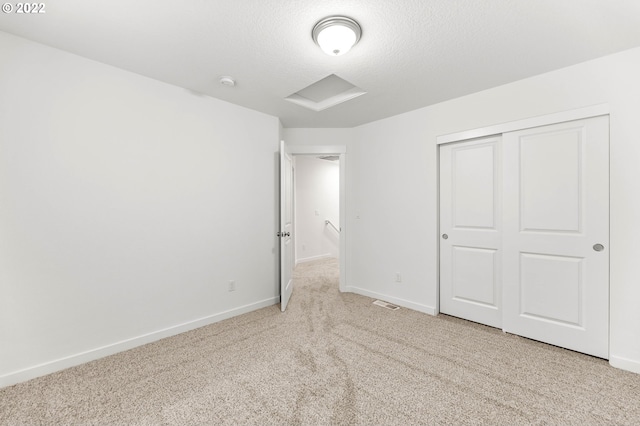 unfurnished bedroom featuring light carpet, a textured ceiling, and a closet